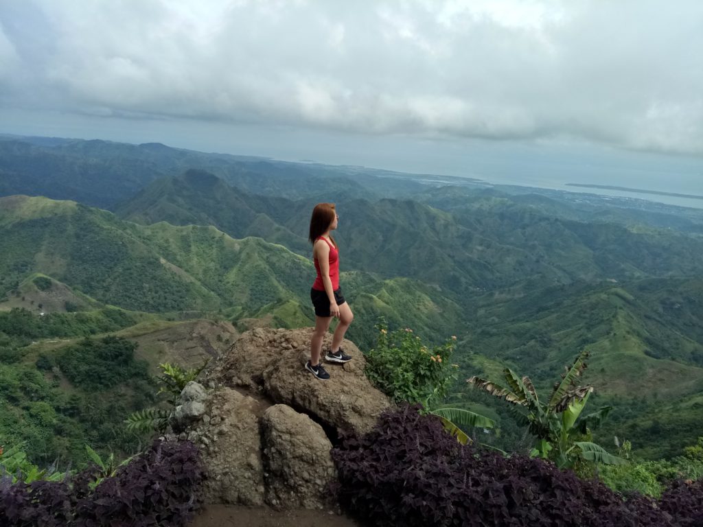 Woman in exercise clothes looks out over a valley and prayers a morning prayer for spiritual strength.