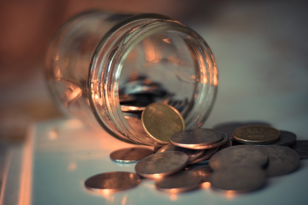 Coins spill out of an overturned jar reminding us that God provides in times of financial stress.