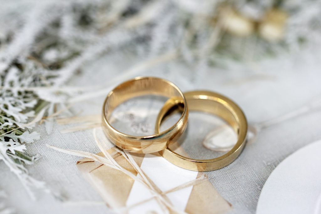 Two gold wedding bands lie on a white tablecloth reminding you to pray a one-minute prayer for marriages.