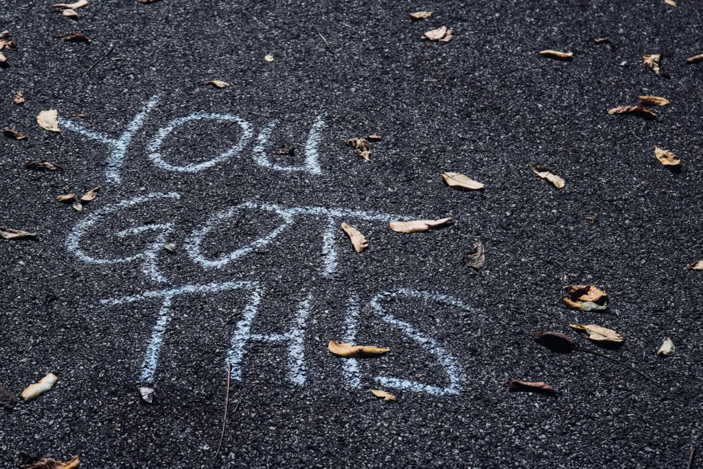 The words "you got this" chalked in white on a leaf-strewn asphalt road remind us to pray a morning prayer for confidence.