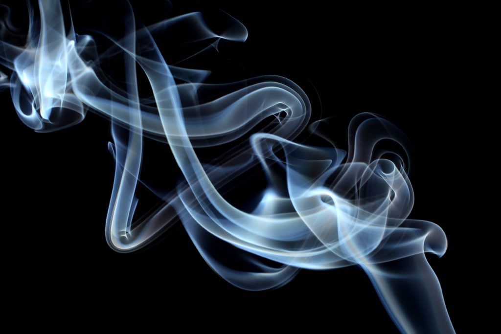 Thin wisps of white smoke float on a black background as a reminder that sacrificial living can ease financial stress.