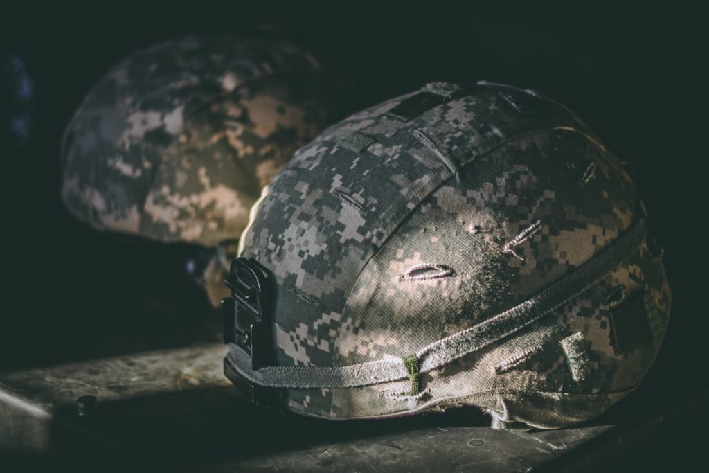 A soldier's helmet sits on the ground in shadows reminding us to pray a prayer for peace.