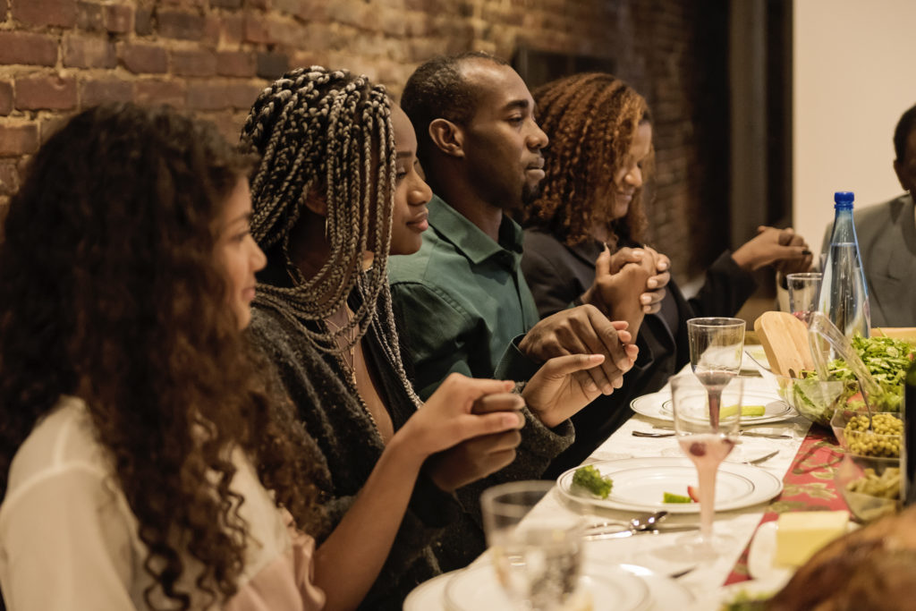 A family gathers around the table for a Thanksgiving prayer.