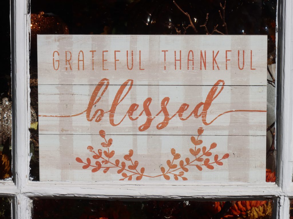 The words "grateful, thankful, blessed" on a wooden sign encourage gratitude in us.