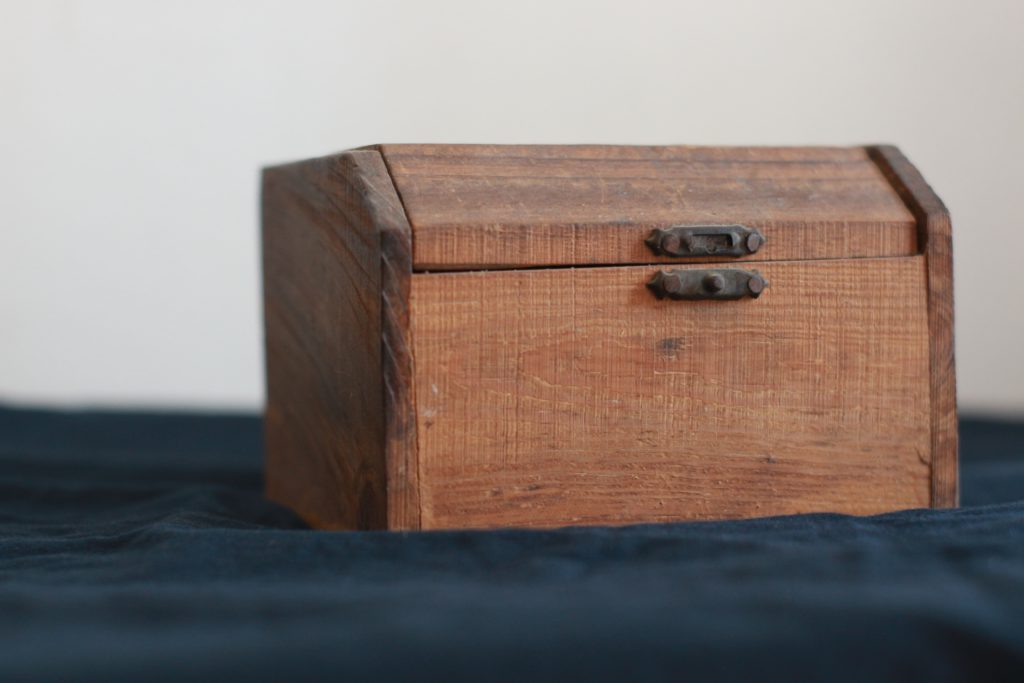 A wooden box sits on a dark blue cloth keeping us from finding financial peace.