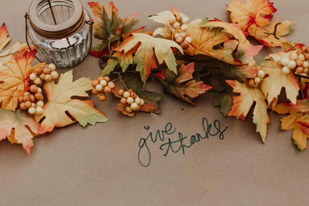 fall leaves on a table surround the words "give thanks" as you pray a Thanksgiving prayer.