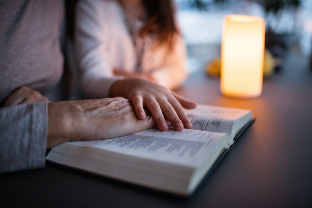 Two people join in reading the Bible together, which helps improve your mental health.