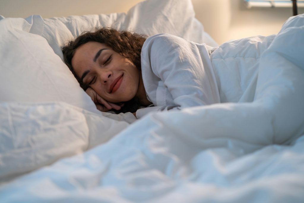 A woman in a white bed has less stress and better sleep as she focuses on God's Word.