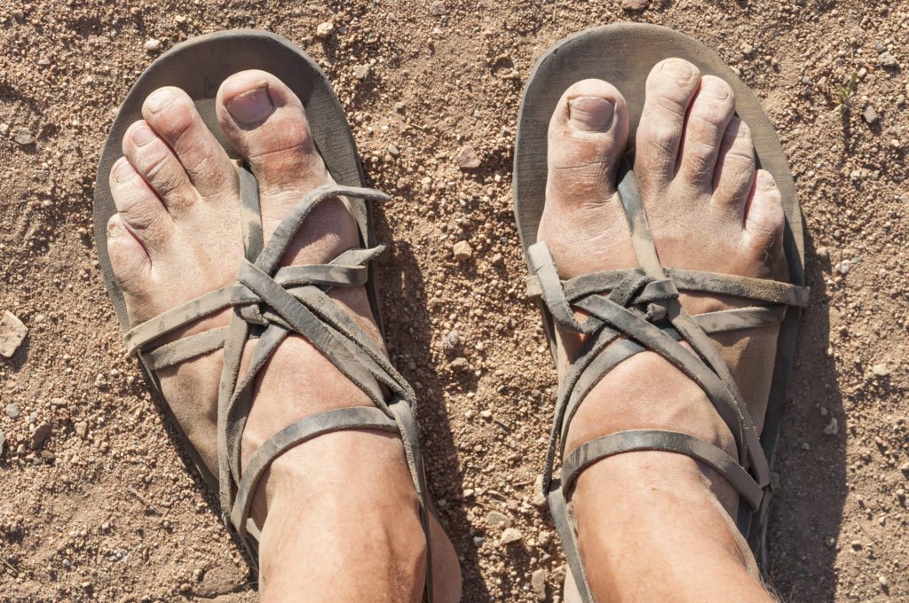 Dusty feet in traditional sandals speak or the armor of God and the power of Scripture
