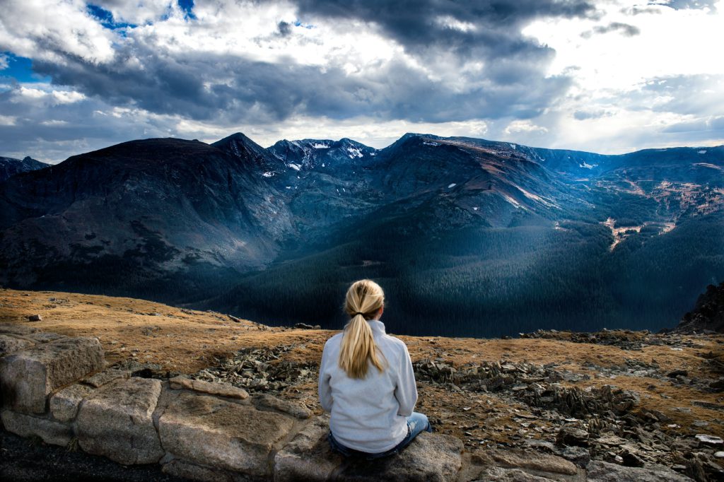 A woman sits in silence looking out over the mountains as she practices Christian meditation for insomnia.