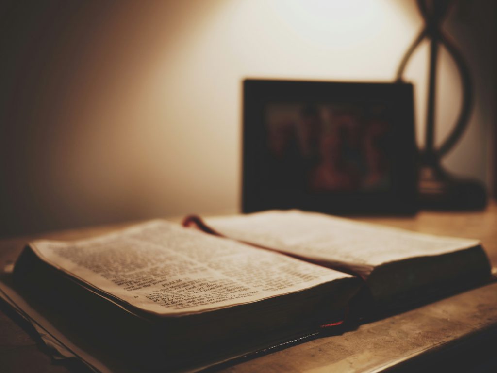 An open Bible by a bedside reminds us to get better sleep by meditating on God's Word.