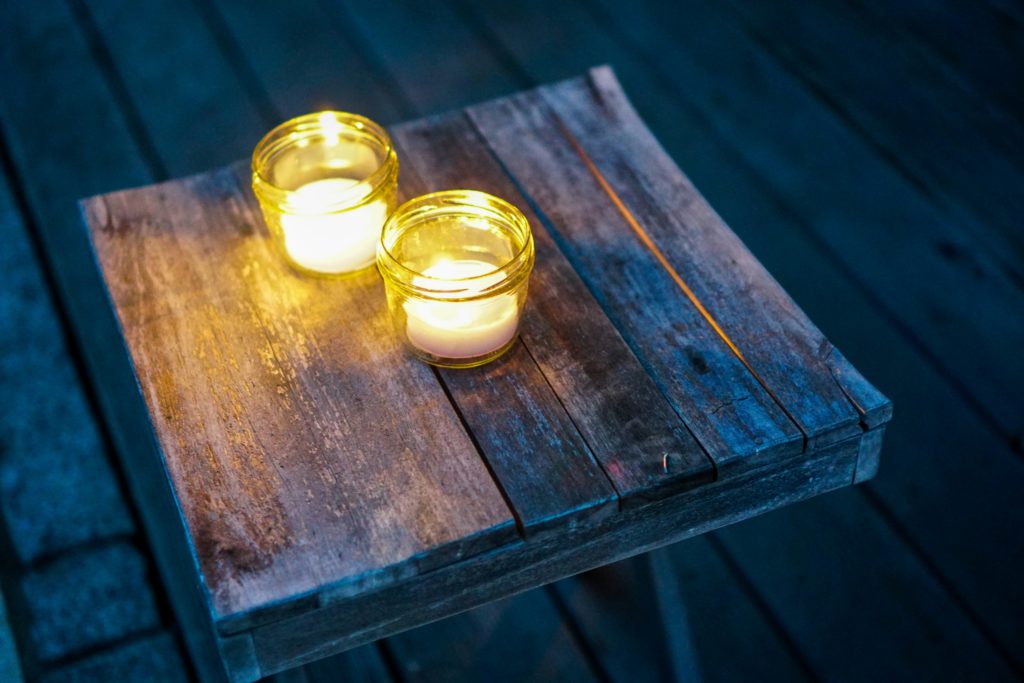 Two candles on a wooden table outside at night make a good place for evening prayers.