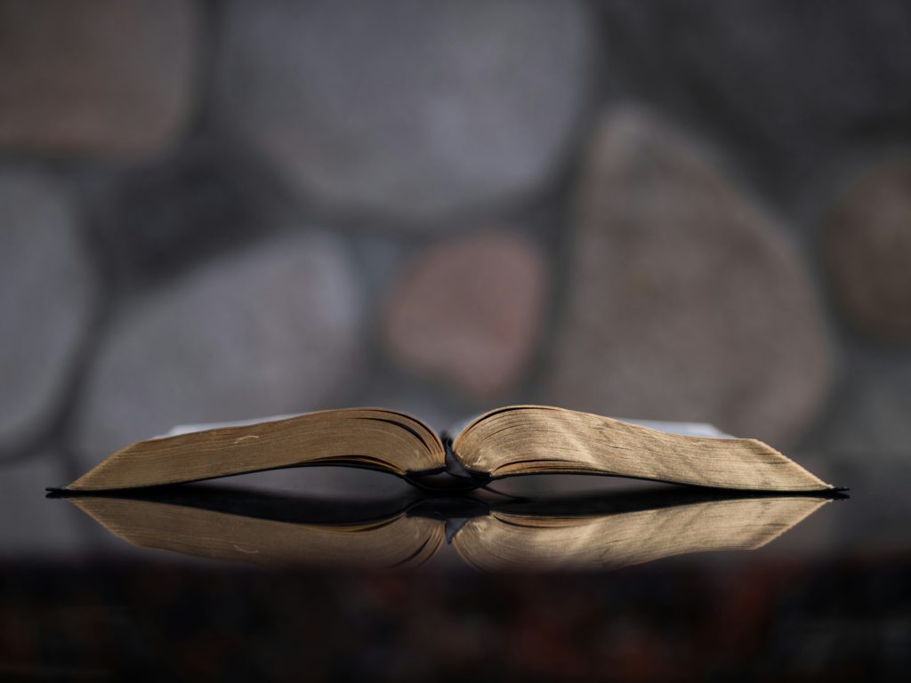 An open Bible on a shiny surface reminds us to focus on gratitude and Scripture to get better sleep.