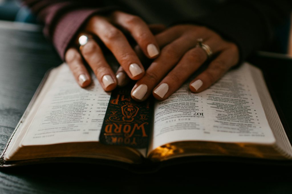 A woman rests her hands on an open Bible as she spends time personalizing the psalms.