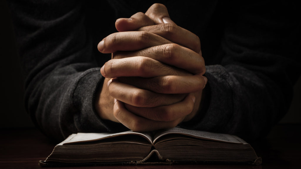 Royalty-Free Stock Photo. Praying hands drawing strength from the nighttime promises in Ephesians.