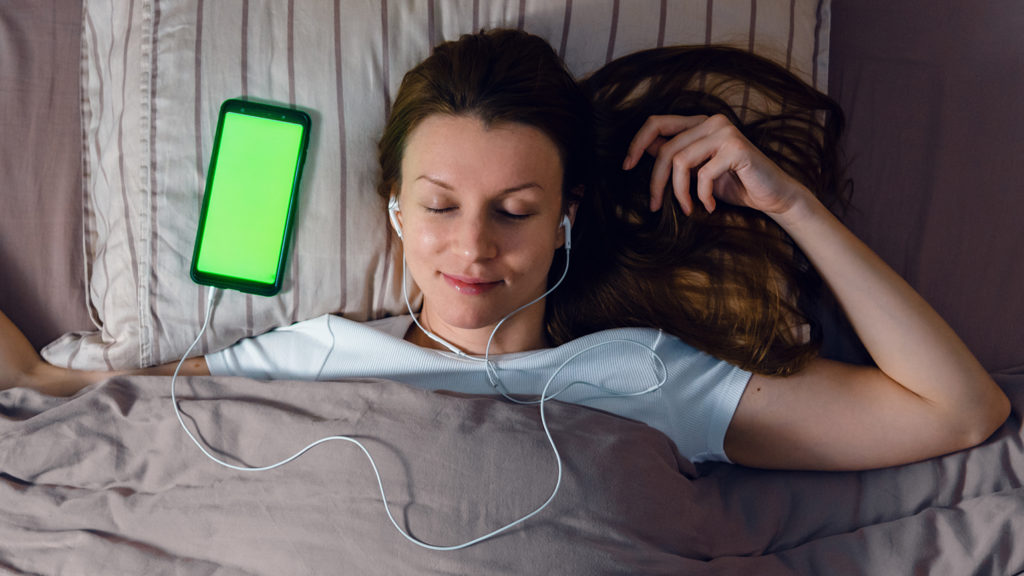 Royalty-free stock photo: A woman eases into a peaceful sleep listening to worship music