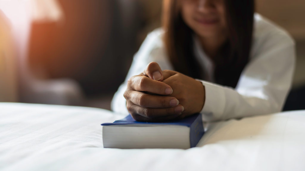 Royalty-free stock photo: A woman prays over her Bible at bedtime