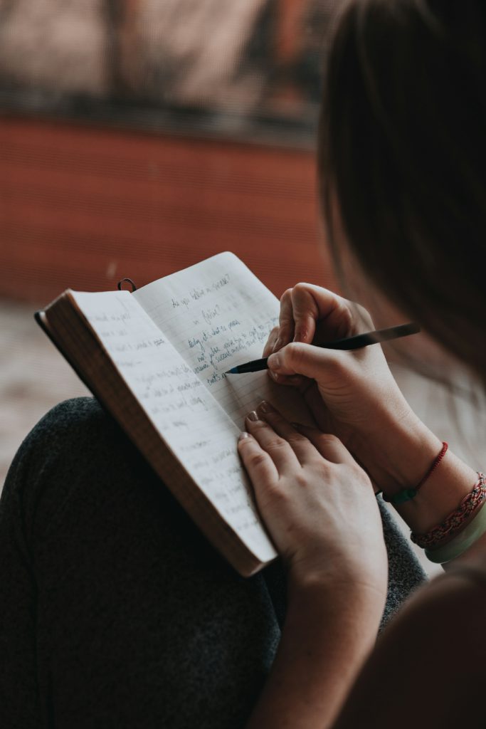 A woman writing in a journal shows how to fuel your faith through reflecting on God's powerful works in your life.