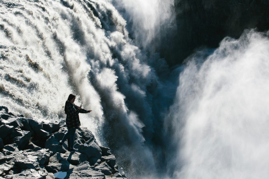 A woman standing before a roaring waterfall experiences God's divine power.