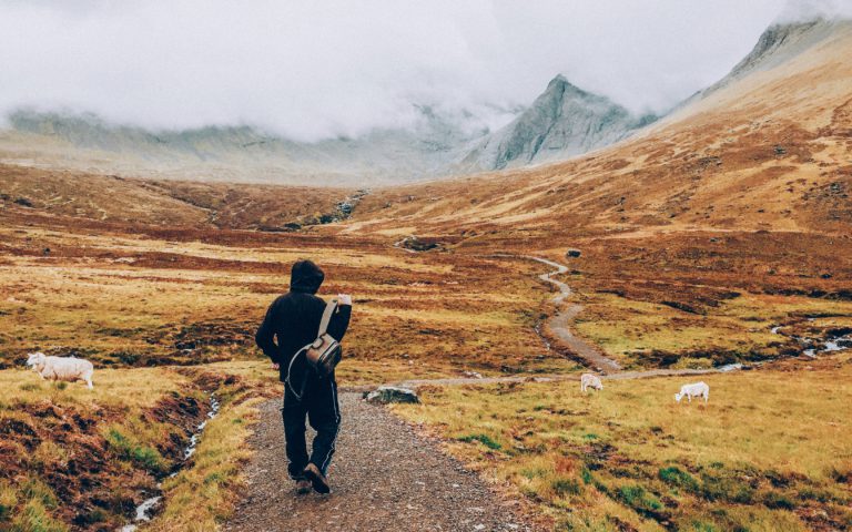 A man hikes a road toward the mountains in a quest for authenticity.