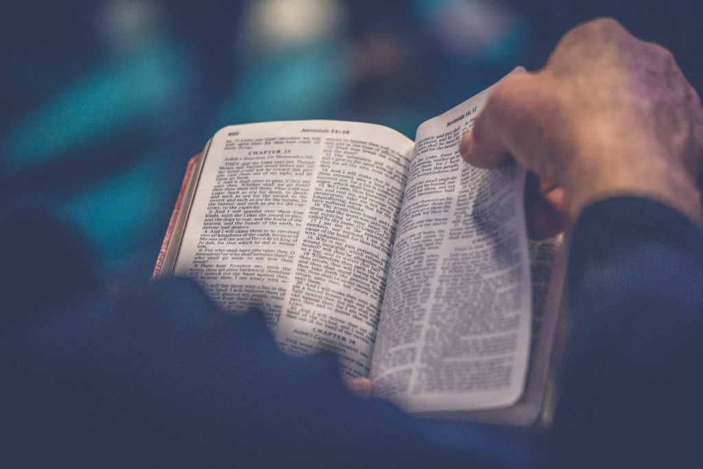 A man's hand turns the pages of a Bible where you can build a belief system rooted in truth.