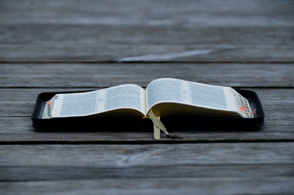 An open Bible on a wooden table helps you answer challenges to faith.