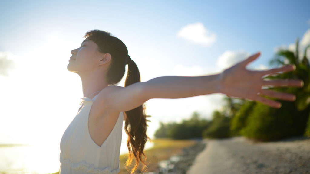 Royalty-Free Stock Photo: Young woman with open arms finding freedom in letting go.