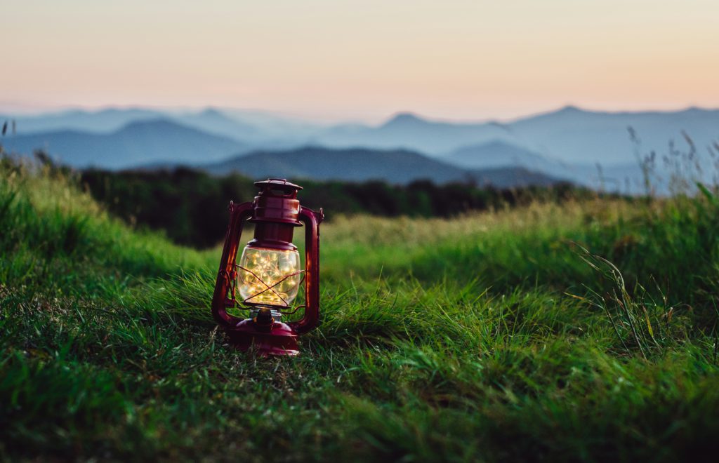 A red lantern sits on a grassy hill in the mountains reminding us that all things are illuminated by God's light.
