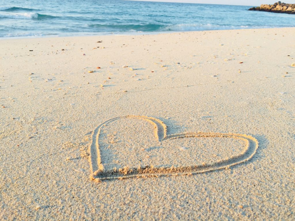 A heart written in the sand on a beach reminds us to overcome offenses with compassion.