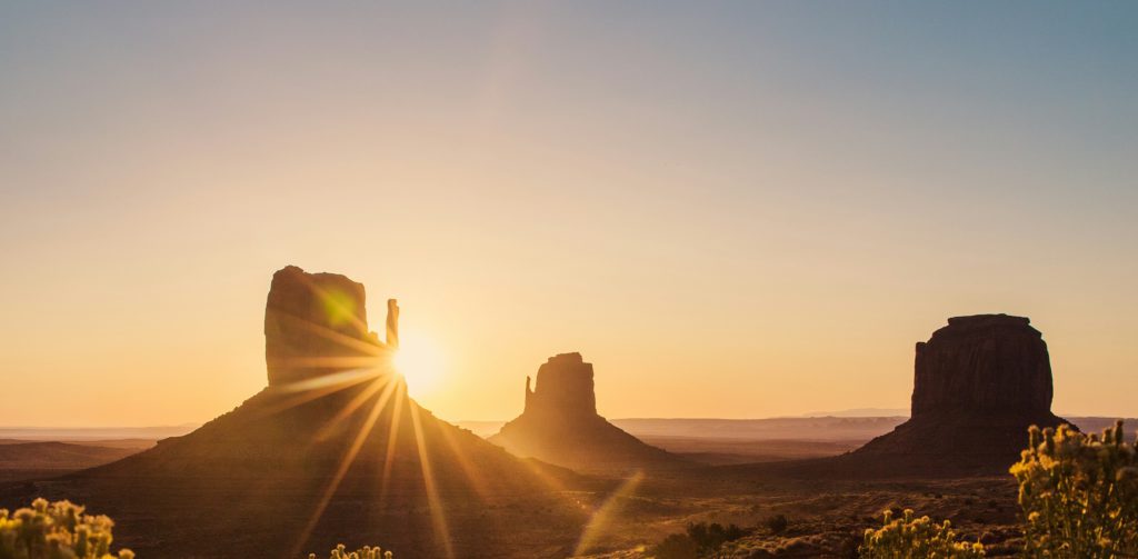 The sun's gold glow behind buttes in the desert remind us to follow the golden rule.