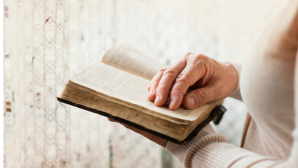 An older woman holds an open Bible in her hands as she discovers her God-given value.