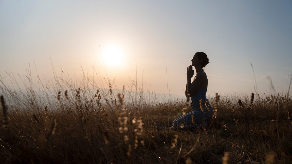 Royalty-Free Stock Photo: Woman praying and turning doubt into devotion at sunset.