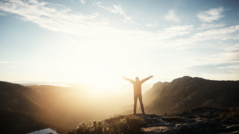 Royalty-Free Stock Photo: Hiker standing on a mountaintop developing an unoffendable character.