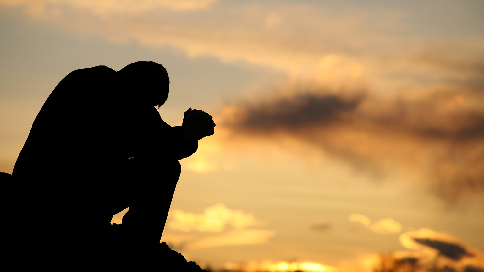Royalty-Free Stock Photo: Man praying and building a resilient faith at sunset.