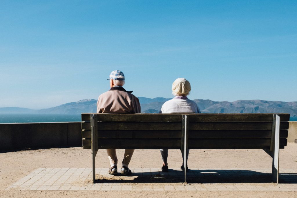 Two older people sit on a bench on a mountain overlook having worked a lifetime at developing an unoffendable spirit.