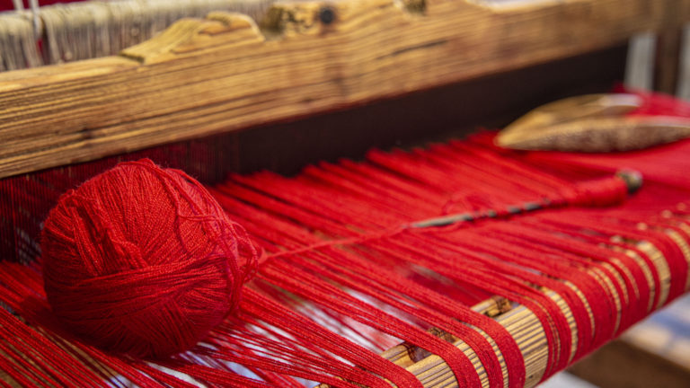 A loom with red yarn illustrates the divine tapestry we are all part of