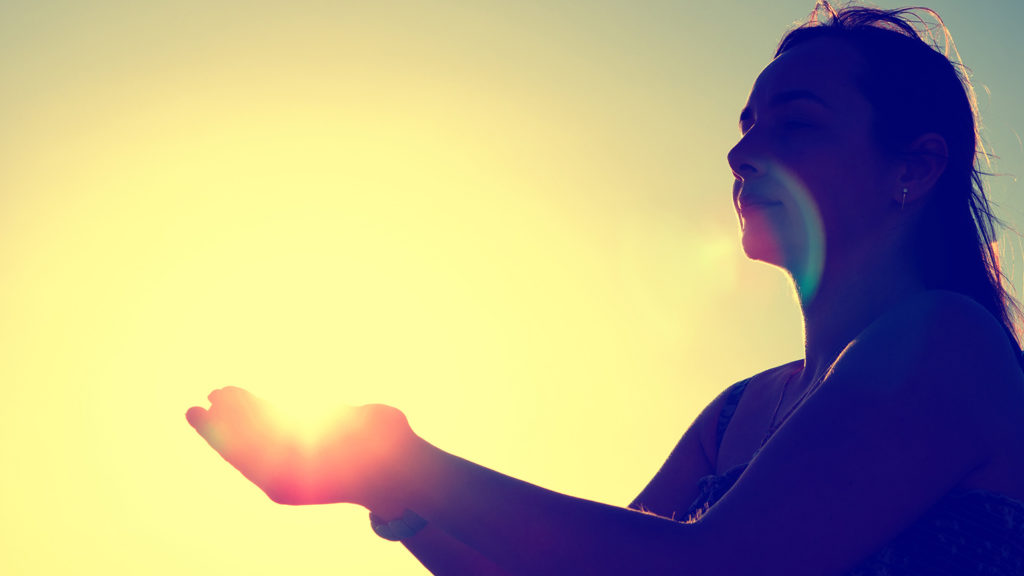 Royalty-Free Stock Photo: Silhouette of woman holding her hands up toward the sunset. 
