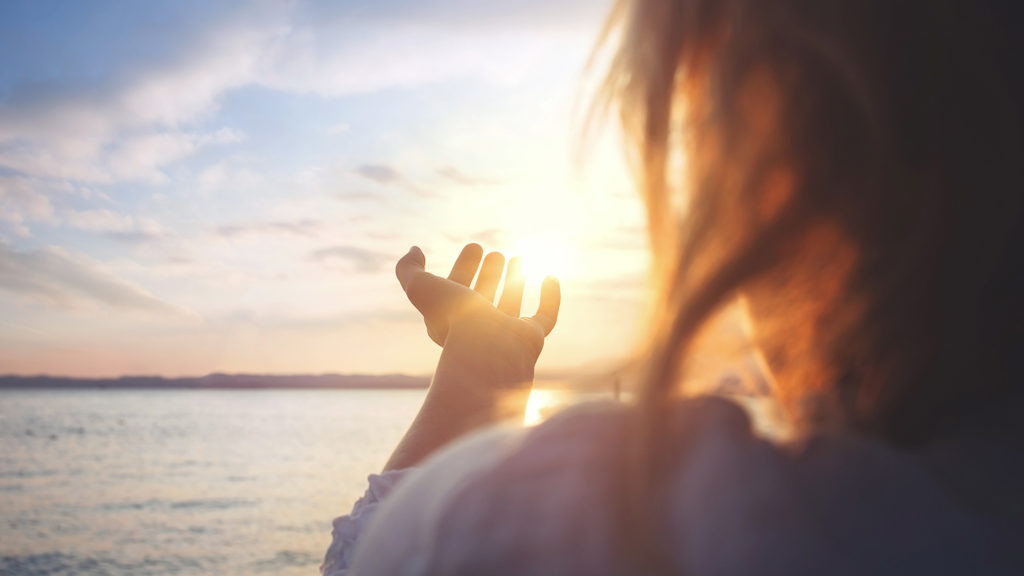 Royalty-Free Stock Photo: Woman reaching towards the sun, embracing God's transforming revelations.