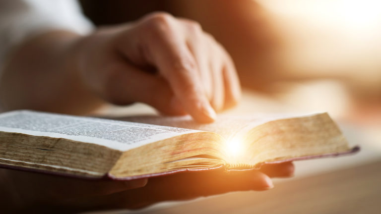Royalty-Free Stock Photo: Woman's hand touching the Bible and reading scripture's lightbulb moments.