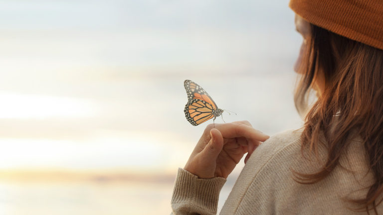 Royalty-Free Stock Photo: Woman holding a butterfly, embracing God's masterpiece.