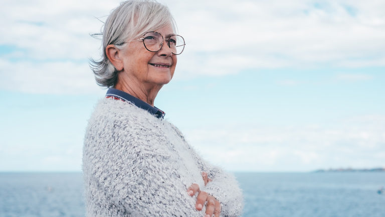 Royalty-Free Stock Photo: Senior woman standing by the sea on her journey to contentment.