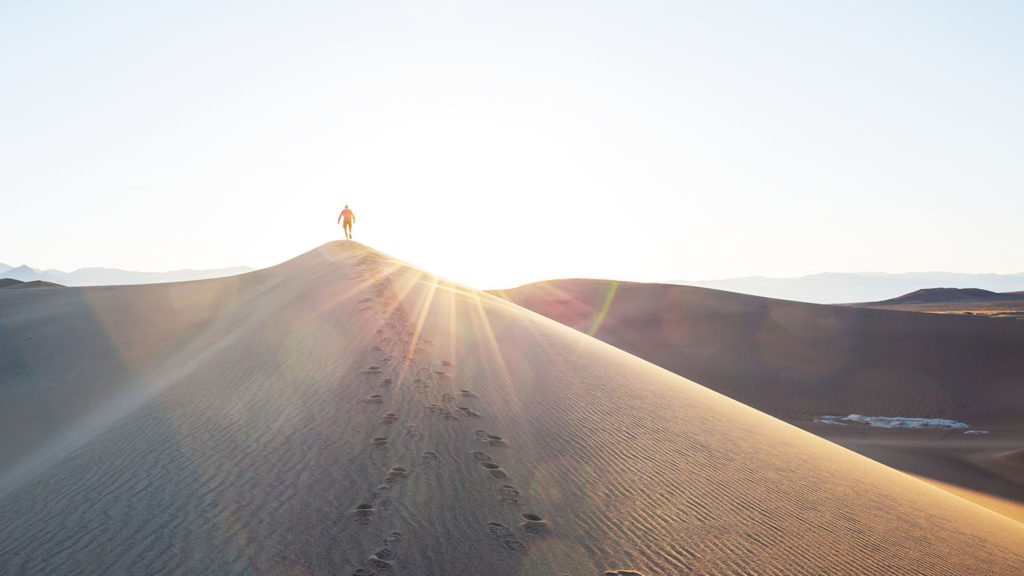 A man walks on sand dunes in Death Valley National Park choosing to live the abundant life.