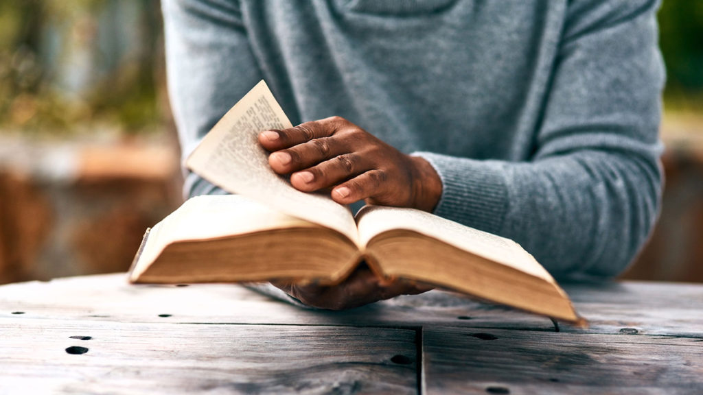 Royalty-free stock photo: A man reads a Bible to find life-altering Scriptures.