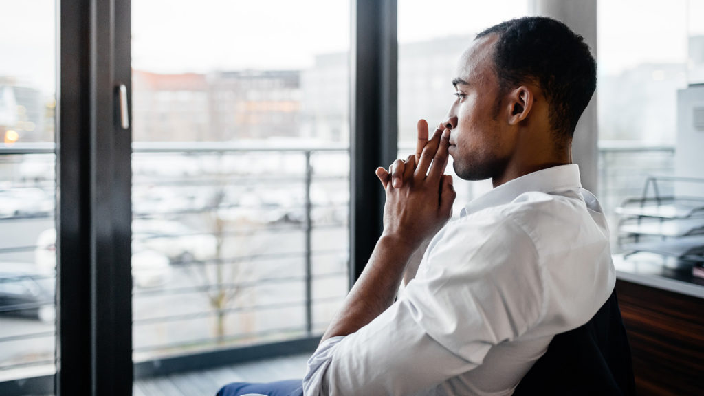 Royalty-free stock image: A man experiencing doubt gazes pensively out a window; Getty Images