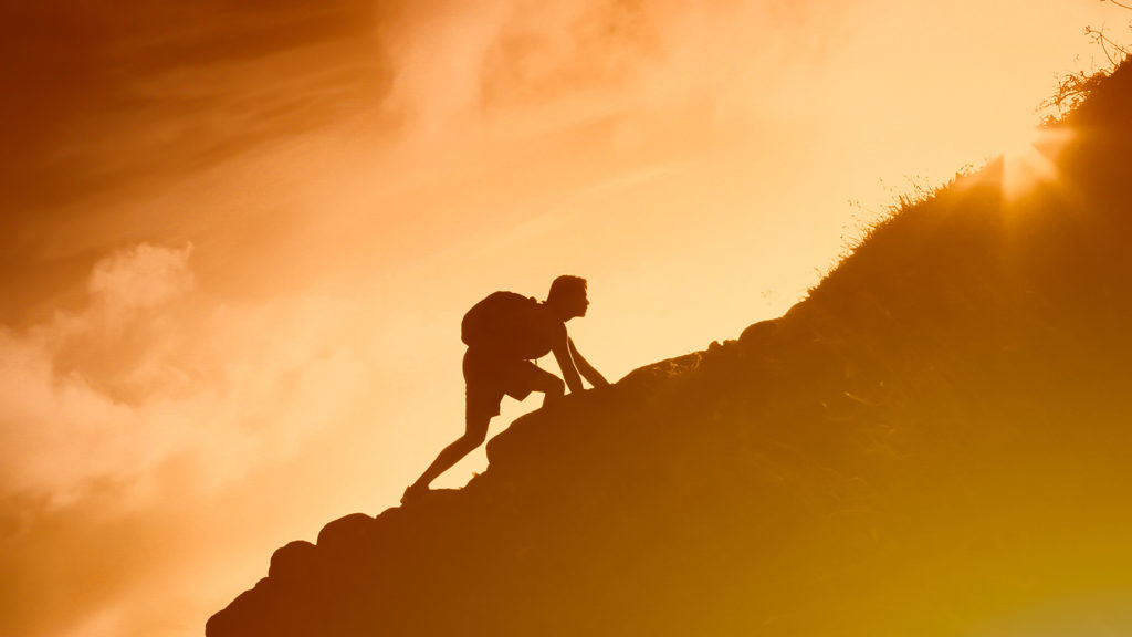 Royalty-Free Stock Photo: Silhouette of a man climbing a mountain and overcoming spiritual hurdles.