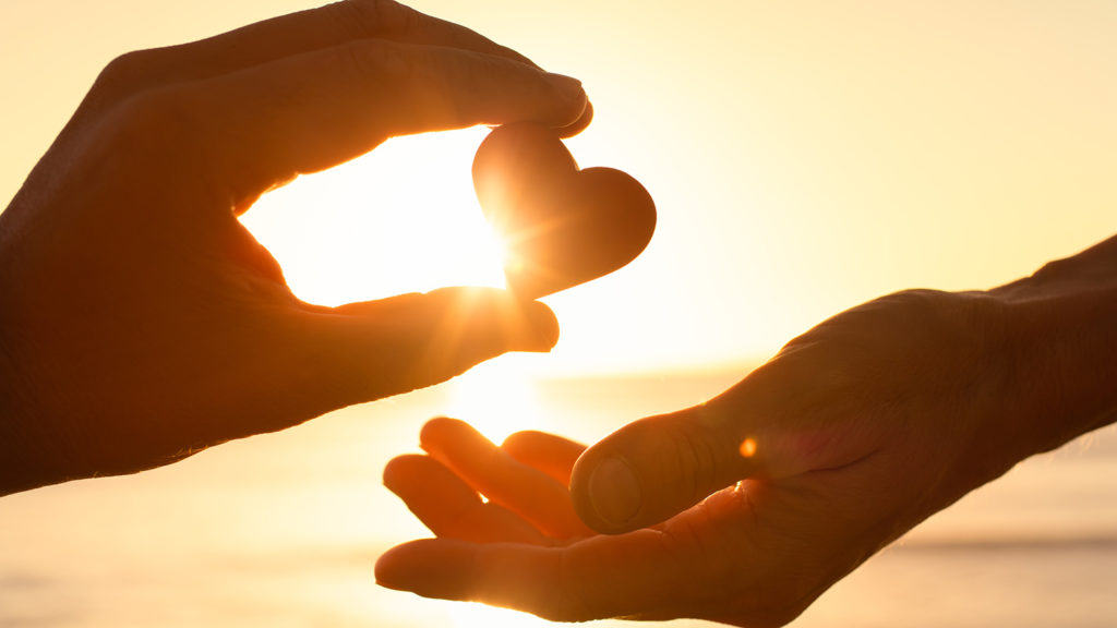 Royalty-Free Stock Photo: Hand passing heart with scriptural truths to another.