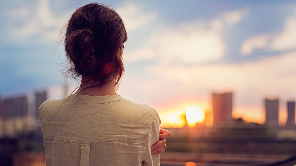 Royalty-free stock photo: A woman greets the sunrise in a city