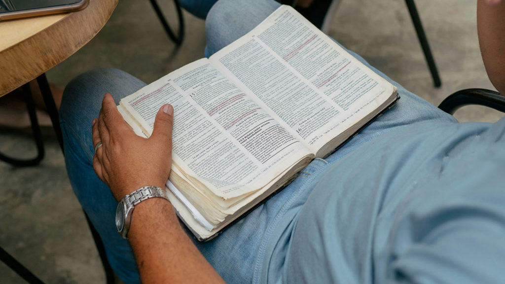 A man sits with an open Bible in his lap as he cultivates a life of faith.