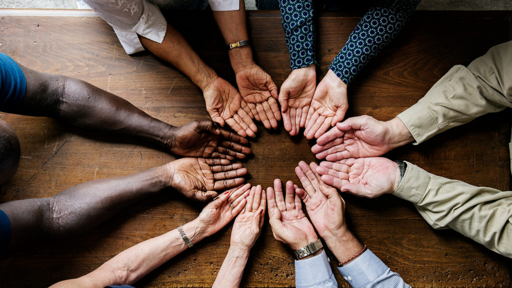 A circle of open hands of all different skin tones shows how we can always be celebrating diversity.