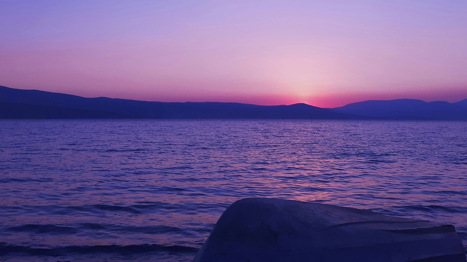 A brilliant purple sunset over the ocean demonstrates the power of unity.